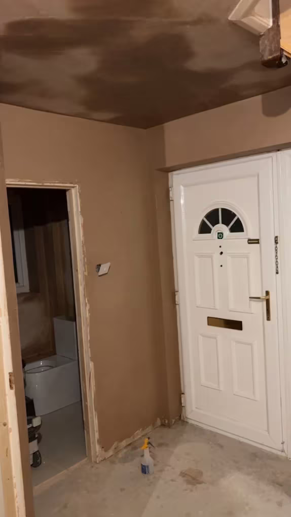 A hallway newly plastered beside the front door, with the downstairs WC off it
