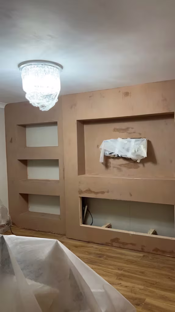 A built-out wall with recessed shelves and a TV recess, freshly plastered